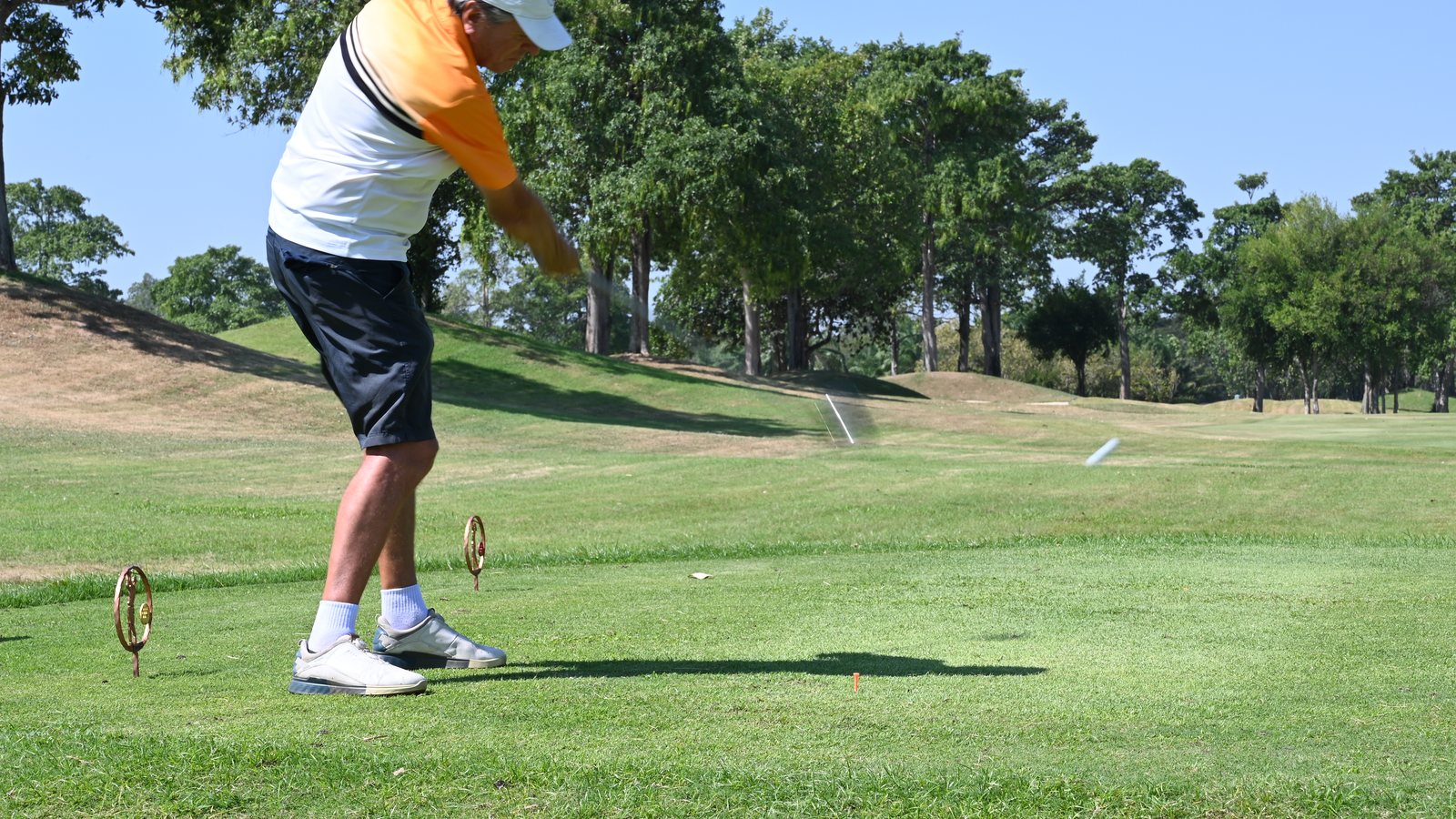 Golfer in mid-swing on a sunny day